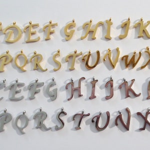 May include: Two rows of gold and silver letter charms, each row displaying the alphabet from A to Z. The charms are in a cursive font style.
