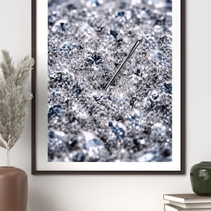 Może przedstawiać: Oprawiony wydruk przedstawiający zbliżenie błyszczącej, teksturowanej powierzchni z licznymi przezroczystymi, fasetowanymi kryształami. Srebrna igła jest włożona w powierzchnię. Kryształy są w odcieniach srebra i niebieskiego.