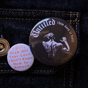 May include: Three round badges with text and graphics. One is black with the word "Untitled" and a figure. Another is light purple with the text "I Gets High Off Your Love I Don't Know How To Behave".