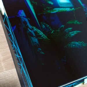 Gros plan sur la bordure du cadre montrant l'effet de glitch géométrique cyan et la texture en relief de l'impression UV sur styroglass.