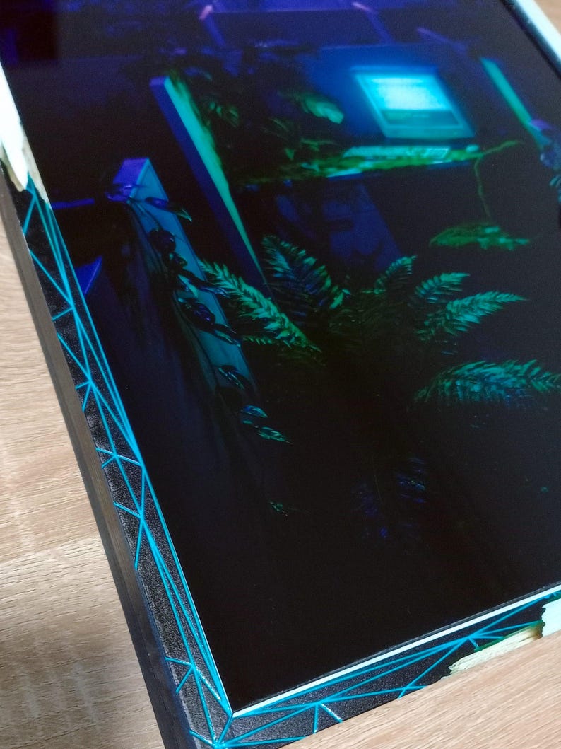 Gros plan sur la bordure du cadre montrant l'effet de glitch géométrique cyan et la texture en relief de l'impression UV sur styroglass.