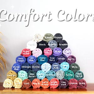 A pyramid-shaped arrangement of rolled-up fabric swatches in various colors, with the text "Comfort Colors" displayed above.