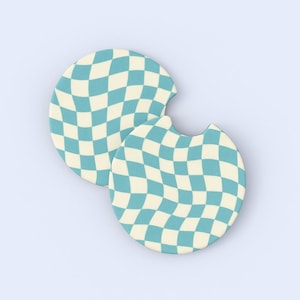 May include: Two round car coasters with a wavy checkerboard pattern in light blue and cream. One coaster has a notch for easy removal from the cup holder. The coasters are made of absorbent material.