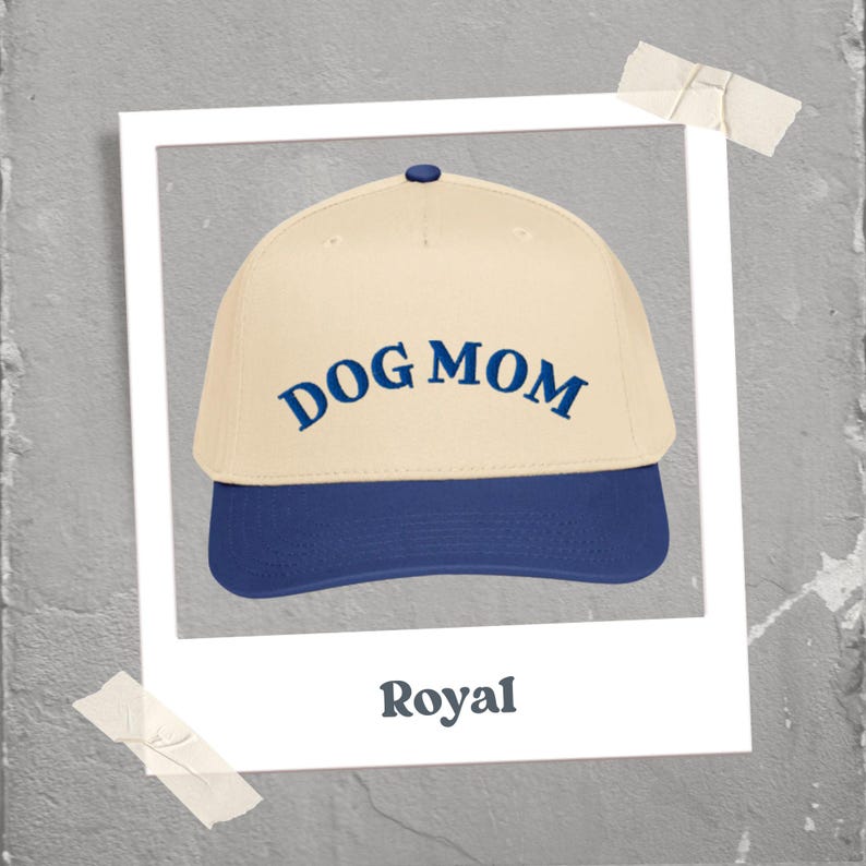 May include: A baseball cap with a cream-colored crown and a royal blue brim. The words "DOG MOM" are embroidered in royal blue across the front. The word "Royal" is printed below the cap.