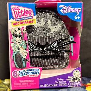 Puede incluir: Una mochila Disney Real Littles con un dise&ntilde;o de Pesadilla antes de Navidad. La mochila negra tiene purpurina plateada y un dise&ntilde;o de Jack Skellington. El embalaje incluye el texto "Real Working Stationery Inside!"
