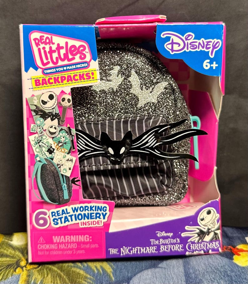 Puede incluir: Una mochila Disney Real Littles con un dise&ntilde;o de Pesadilla antes de Navidad. La mochila negra tiene purpurina plateada y un dise&ntilde;o de Jack Skellington. El embalaje incluye el texto "Real Working Stationery Inside!"