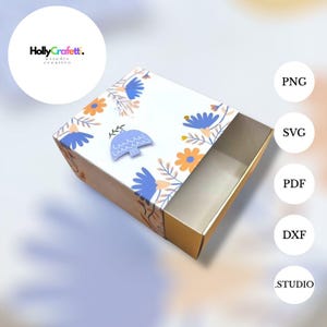 May include: A decorative box with a floral design in blue and orange. The box has a white lid with a blue bird and the text "Holly Crafett." The box is open, revealing a gold interior. The image also includes the file types: PNG, SVG, PDF, DXF, and .STUDIO.