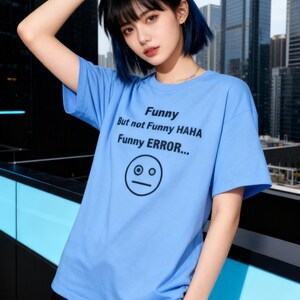 Puede incluir: Una camiseta azul claro con el texto "Funny But not Funny HAHA Funny ERROR..." y un gr&aacute;fico de cara simple. La camiseta tiene mangas cortas y cuello redondo.