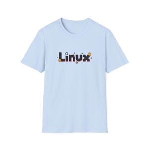 Puede incluir: Una camiseta azul claro con la palabra "Linux" en una fuente estilizada. El texto es negro con detalles en rojo y est&aacute; decorado con peque&ntilde;os iconos, incluyendo un engranaje, una estrella y una carita sonriente.
