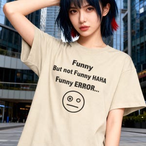 Puede incluir: Camiseta beige con el texto "Funny But not Funny HAHA Funny ERROR..." y un gr&aacute;fico de cara de sorpresa. La camiseta est&aacute; hecha de un material suave, adecuada para el uso diario.