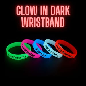 Può includere: Cinque braccialetti in silicone luminescenti al buio in verde, rosa, blu, azzurro e rosso. Il testo GLOW IN DARK WRISTBAND appare in alto. I braccialetti presentano scritte nere che recitano Your Custom T, Fundraising, Support, Team Jenna e Cancer Awareness.