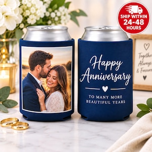 May include: Two navy blue foam can coolers. One features a printed photograph of a couple embracing, while the other displays the white text Happy Anniversary to many more beautiful years with a heart icon. Both have silver metal rims.