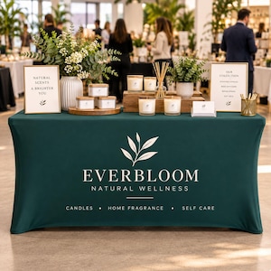 May include: A dark green fitted tablecloth featuring the white logo and text EVERBLOOM NATURAL WELLNESS, CANDLES, HOME FRAGRANCE, SELF CARE. The table displays scented candles, reed diffusers, and signs reading NATURAL SCENTS A BRIGHTER YOU.