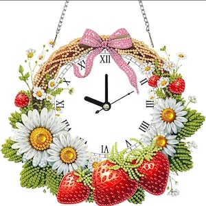 Puede incluir: Un reloj de pared redondo con esfera blanca, números romanos negros y manecillas negras. El marco está decorado con una corona de margaritas blancas, hojas verdes y fresas rojas. Un lazo rosa brillante en la parte superior con una cadena plateada.