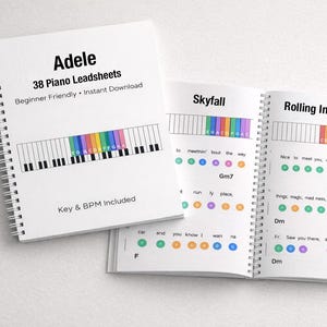Può includere: Un libro rilegato a spirale bianco intitolato "Adele 38 Piano Leadsheets" con il testo "Beginner Friendly + Instant Download". Il libro aperto mostra spartiti per "Skyfall" e "Rolling In The Deep". Sono inclusi diagrammi colorati dei tasti del pianoforte.