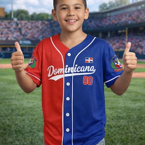 Może przedstawiać: Koszulka baseballowa z czerwono-niebieskim wzorem w bloki kolorów. Koszulka zawiera napis "Dominicana" w białym skrypcie, numer "00" oraz flagę Dominikany. Posiada białe guziki i wykończenia.