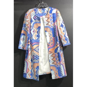 May include: A long, blue and orange patterned coat with a white lining. The coat has a geometric design with a variety of shapes and colours.