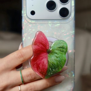 May include: A set of three ceramic mugs with a speckled, cream-colored glaze. Each mug features a different hand-painted design: a blue and green leaf, a yellow flower, and a red berry. The mugs have a simple, modern design.