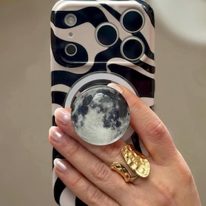 May include: A set of three ceramic mugs with a speckled, matte finish. The mugs are in shades of cream, light gray, and dark gray. Each mug has a simple, minimalist design and a rounded handle.