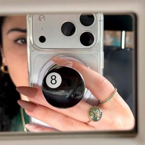 May include: A white ceramic mug with a black handle and the text "But First, Coffee" in a black, bold font. The mug is on a white surface.