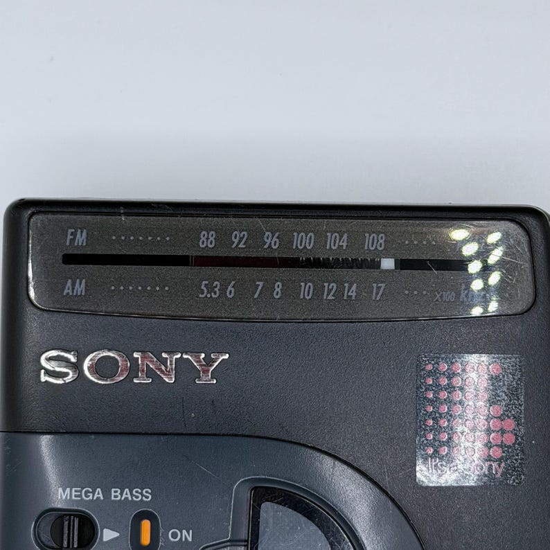May include: A close-up of a black Sony radio. The radio has an FM and AM dial, with the FM dial showing frequencies from 88 to 108. The radio also has a "MEGA BASS" feature and an "ON" switch.