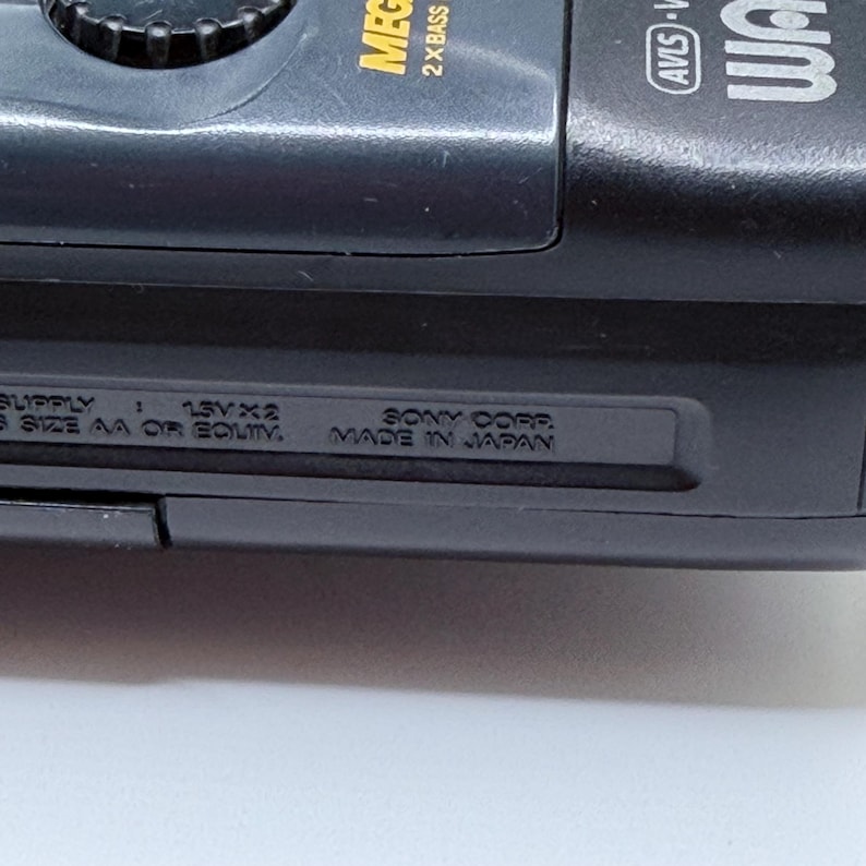 May include: Close-up of a black Sony Walkman. The text "MEGA BASS" and "2 X BASS" is visible. The text "SONY CORP. MADE IN JAPAN" is also visible.