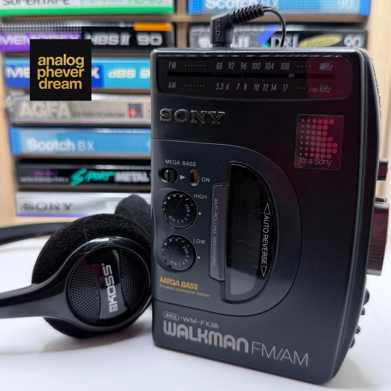 May include: A black Sony Walkman FM/AM radio with a pair of black headphones. The Walkman has a Mega Bass feature and a digital display. The text "analog phever dream" is in the upper left corner.