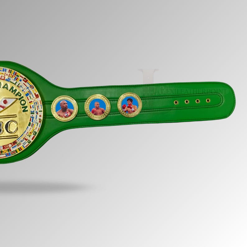 May include: A green leather boxing championship belt with gold accents. The belt features three circular medallions with portraits of boxers. The main plate displays the letters "WBC" and the word "CHAMPION" in gold.