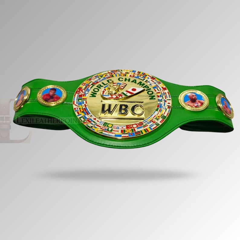 May include: A green World Boxing Council (WBC) championship belt. The belt features a large gold center plate with the WBC logo and the words "World Champion." It has circular medallions with boxer portraits and a green leather strap.