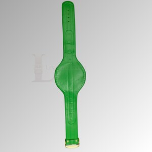 May include: A bright green leather girth with a gold-colored buckle. The girth has a wide, rounded center section and a narrower strap on each end. The leather has a textured appearance.