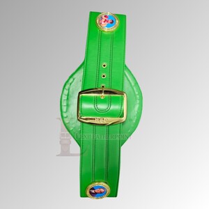 May include: A green boxing championship belt with gold-colored accents. The belt features a large gold buckle and two circular medallions with images. The text "WBC" is visible on the buckle.