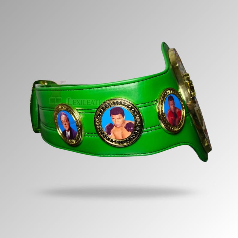 May include: A green boxing championship belt with gold accents and three circular medallions featuring portraits. The belt is made of leather and has a curved design. The text "Lexileather" is visible on the belt.