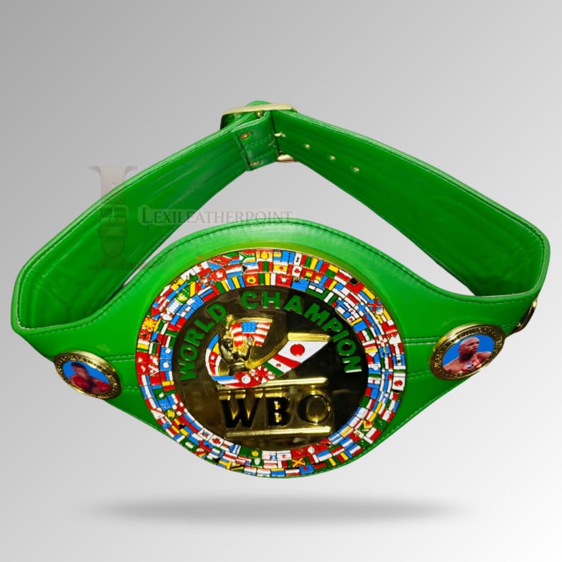 May include: A green leather World Boxing Council (WBC) championship belt. The belt features a gold center plate with the words "WORLD CHAMPION" and "WBC". The center plate is surrounded by flags of different countries. Two circular medallions with portraits are on each side.