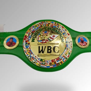 May include: A green and gold World Boxing Council (WBC) championship belt. The belt features a large gold center plate with the WBC logo and the words "WORLD CHAMPION". Two smaller gold plates on either side feature images of boxers.