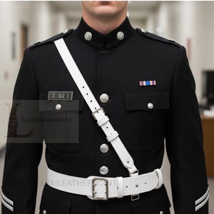 May include: A black military uniform featuring a white belt and shoulder strap. The uniform has silver buttons and a name tag reading "X. SIL 1". A small ribbon with blue, white, and red stripes is pinned on the chest.