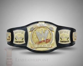 May include: A black and gold WWE Championship belt with a large gold center plate featuring a diamond-studded "W" and the word "CHAMPION". The belt has gold side plates and is made of black leather.