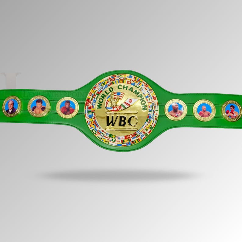 May include: A green World Boxing Council (WBC) championship belt. The belt features a gold center with the words "World Champion" and "WBC". The belt has several circular medallions with portraits of boxers. The belt is green with gold accents.