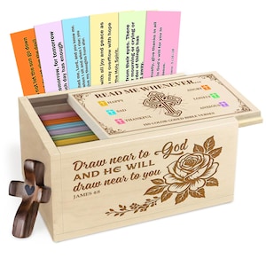 Peut inclure: Boîte en bois avec couvercle à charnière, contenant des versets bibliques à code couleur. La boîte présente une fermeture en forme de croix et un motif de rose décoratif. Le couvercle indique "Read Me Whenever..." et comprend des catégories comme "Happy" et "Sad".