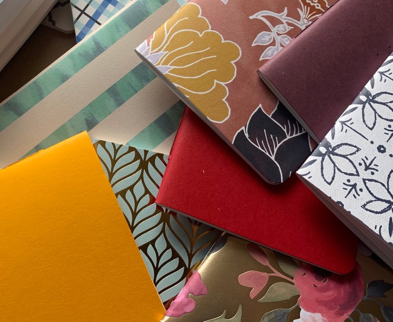 Puede incluir: Una pila de peque&ntilde;os cuadernos coloridos con varias cubiertas estampadas. Las cubiertas incluyen dise&ntilde;os florales, patrones geom&eacute;tricos y colores s&oacute;lidos.