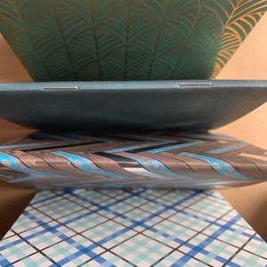 Puede incluir: Cuatro cuadernos con diferentes cubiertas estampadas. El cuaderno superior tiene una cubierta verde con un patr&oacute;n de hojas doradas. El segundo cuaderno tiene una cubierta azul oscuro. El tercer cuaderno tiene una cubierta marr&oacute;n con un patr&oacute;n de rayas azules y blancas. El cuaderno inferior tiene un patr&oacute;n de cuadros azules y blancos.