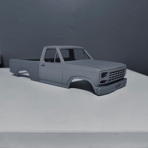 May include: A gray model of a classic pickup truck, showcasing the cab and bed. The truck features a detailed front grille, bumper, and wheel wells, with a focus on the vehicle's body lines. The model is set against a neutral background.
