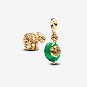 May include: Two gold-toned jewellery charms. One charm is a coiled snake with clear pavé stones. The second charm features a gold snake with a small pink stone, wrapped around a smooth, circular green bead, with the text ALE MET engraved on the bail.