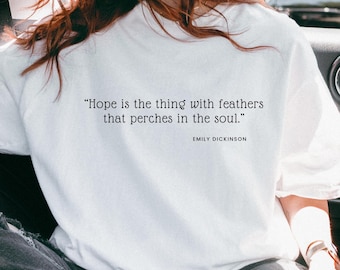 May include: White sweatshirt with the quote "Hope is the thing with feathers that perches in the soul." by Emily Dickinson printed on the back. The sweatshirt is a solid white color.