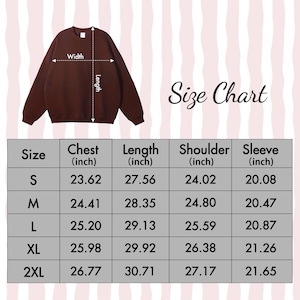 Peut inclure: Un sweat-shirt marron fonc&eacute; &agrave; col rond affich&eacute; au-dessus d'un tableau de tailles. Le tableau indique les tailles S &agrave; 2XL avec les mesures correspondantes en pouces pour la poitrine, la longueur, l'&eacute;paule et la manche.