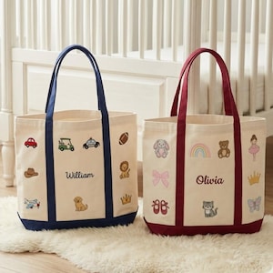 May include: Two canvas tote bags with cream-colored fabric and colorful embroidered designs. One bag has navy blue handles and trim, the other has burgundy. Each bag is personalized with a name, and features various embroidered images.