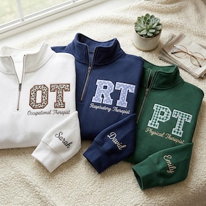 May include: Three quarter-zip sweatshirts in white, navy blue, and dark green. Each features embroidered block letters OT, RT, or PT with patterns, job titles, and personalized names Sarah, David, or Emily embroidered on the sleeves.
