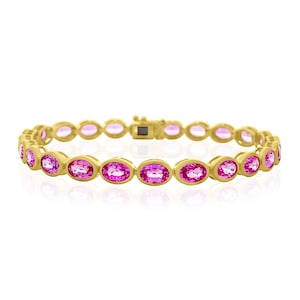 May include: A gold bracelet featuring oval-cut pink gemstones. The gemstones are set in individual bezels, creating a continuous line of color. The bracelet has a secure clasp and is displayed against a white background.