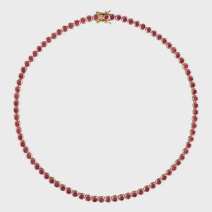 May include: A gold necklace set with a continuous line of round, bright pink gemstones. The necklace has a delicate clasp, and the gemstones are evenly spaced along the chain.