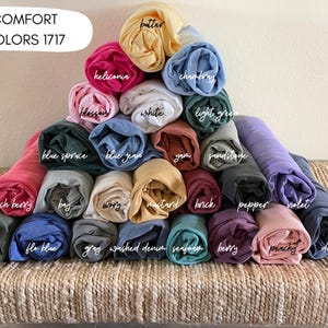 A pyramid-shaped arrangement of rolled-up fabric swatches in various colors, including pink, blue, green, yellow, and purple, with each color labeled.