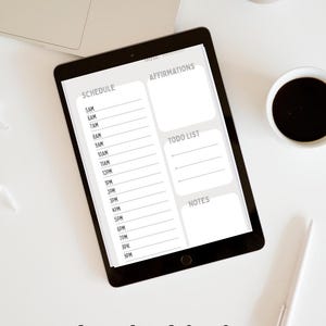 Könnte beinhalten: Ein schwarzes Tablet mit einer digitalen Tagesplaner-Vorlage mit den Abschnitten SCHEDULE, AFFIRMATIONS, TODO LIST und NOTES. Der Zeitplan listet die Stunden von 5AM bis 9PM auf. Der Text download for free und BlopiStudios erscheint unter dem Tablet.